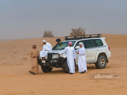 Men chatting around the car
