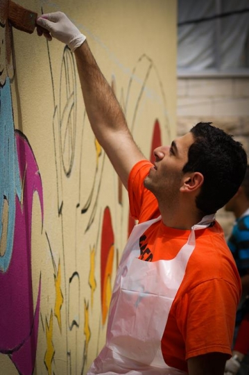 male volunteer painting the wall of kindergarten in jordan