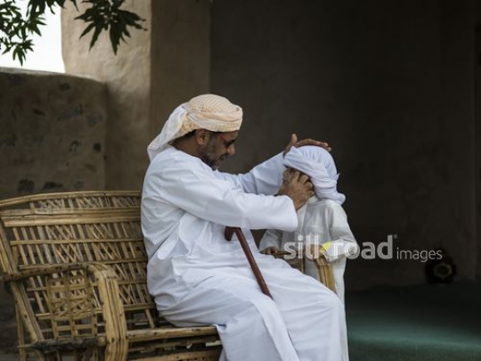 Old man fixing costume of his grandson|-