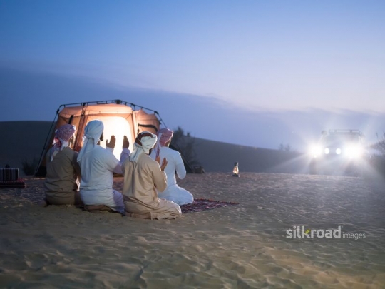 men seated in prayer in the desert camp