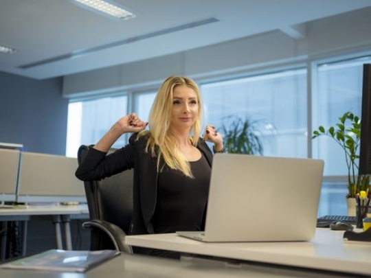 Business woman sitting by her desk stretching|