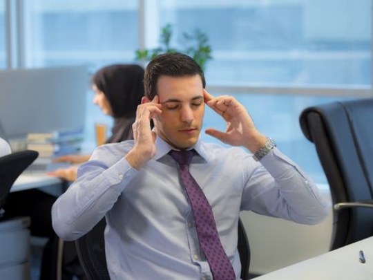 Business man sitting by the desk with a headache|-