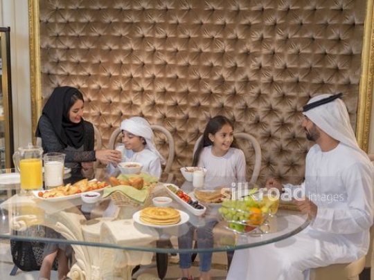 Arab parents sitting with their kids on the breakfast table|