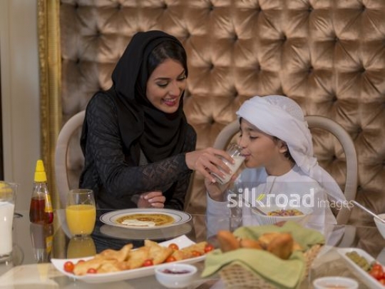 Arab woman giving the young boy a glass of milk to drink|
