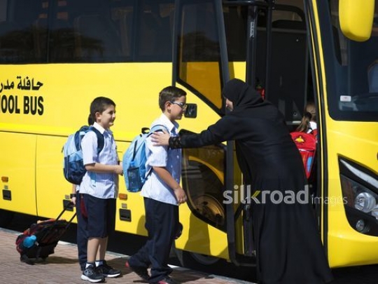 Young Students entering the bus with the help of the supervisor|-
