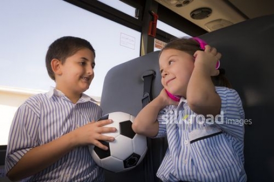 Arab student carrying a football and a Western Student listening to music |-