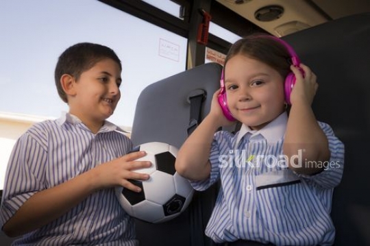 Middle Eastern student looking at the girl listening to her music |-