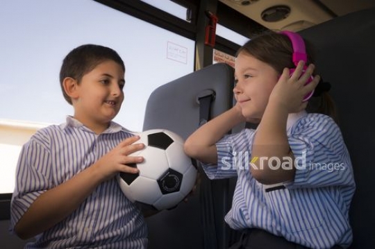Middle Eastern boy looking at the student listening to her music |-