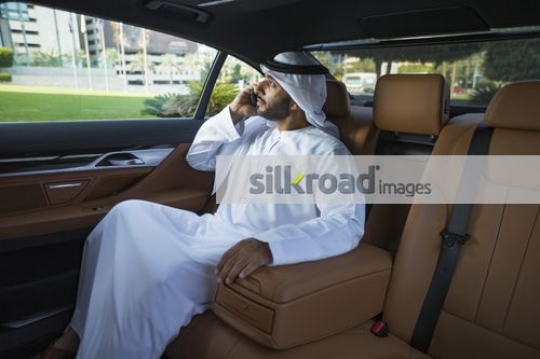 Arab Businessman sitting inside the luxury car talking on the phone|