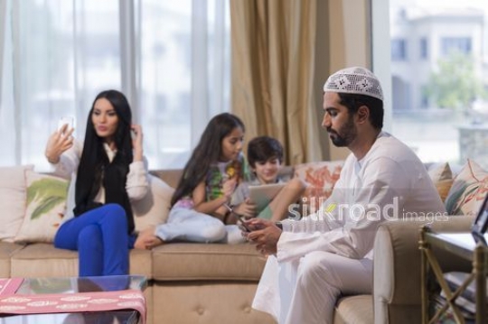 Middle Eastern woman taking a selfie sitting with the young kids and the Middle Eastern man|