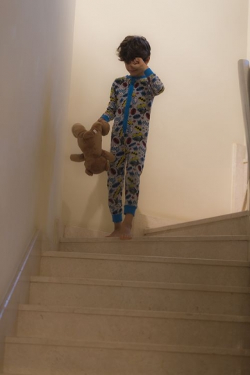Young arabian kid walking down the stairs dressed in his pajamas |-