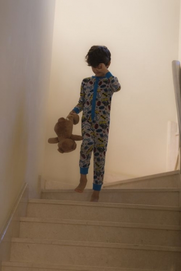 Arabian boy dressed in his pajamas walking down the stairs |-
