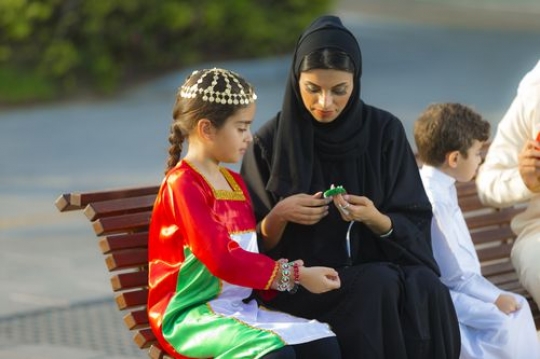 Mother helping her child with her bracelets while the son and father are in the background|-