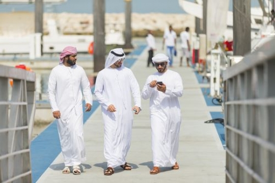 Men dressed in the traditional UAE attire walking towards the dock|
