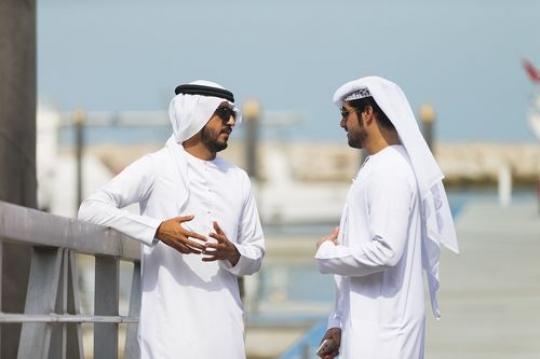 Middle eastern men standing by the dock talking to each other|
