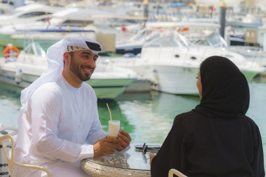 Arab woman and man sitting outside and talking to each other|