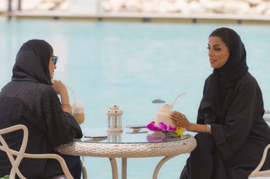 Women sitting outside and talking to each other while having coffee|