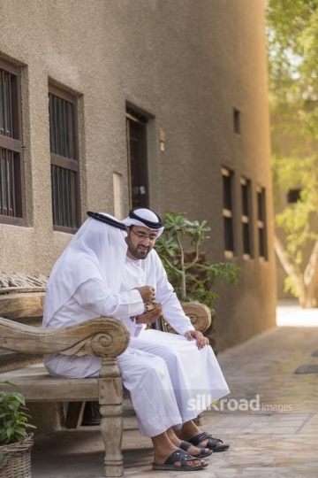 Arab grandfather and son sitting together on the bench|-