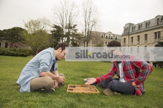 Friends sitting on the grass together playing a game |