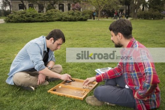 University friends sitting on the grass playing a game |
