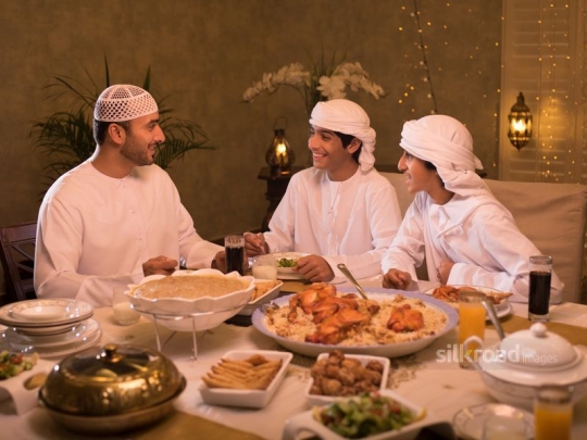 father with sons chatting over iftar|-