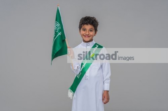 Middle Eastern boy carrying a Saudi flag