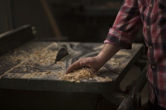 Man removing the wood dust from the table