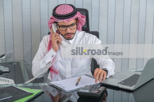 Middle Eastern man talking on the phone working