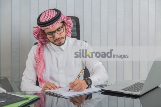 Arab Businessman writing on the notepad|