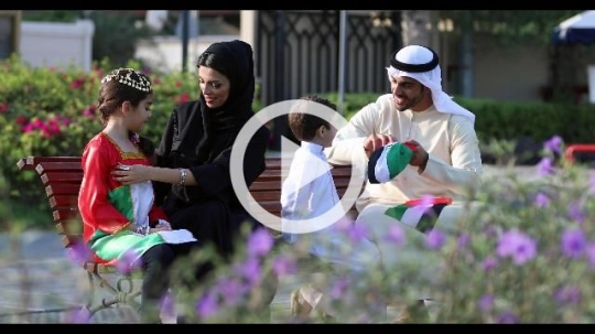 Middle Eastern family sitting on the bench celebrating the UAE National Day|