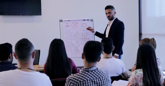 Group of students writing notes in class listening to the professor |-