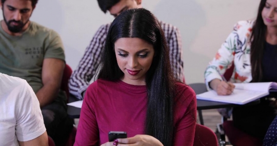 Middle Eastern woman using her mobile in the classroom|-