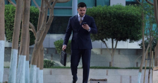 Western Businessman answered the phone call walking with a laptop bag|-