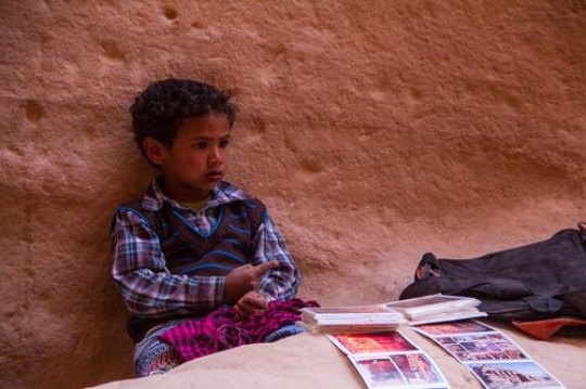 Bedouin boy selling print out of petra images