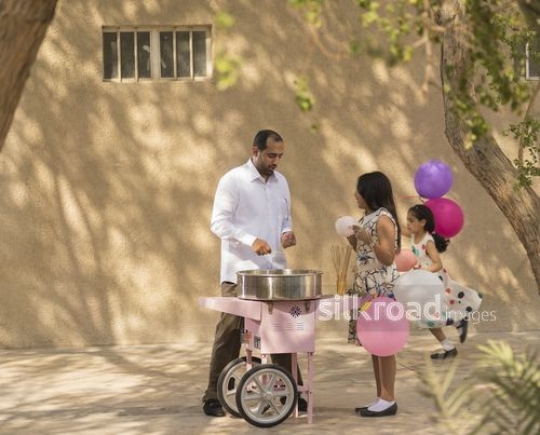 Arab father talking to the girl while the young girl is running in the background|-