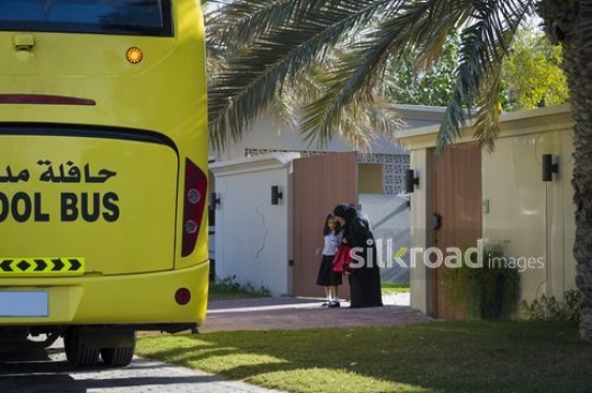 Arab mother dropping her daughter to the school bus|-