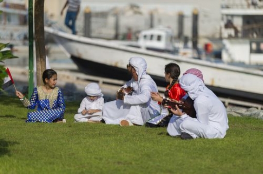 Middle eastern family and friends sitting on the grass celebrating national day|-