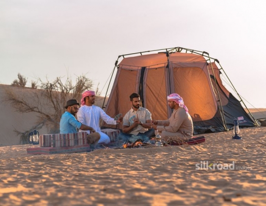 Group of friends playing cards in desert camp