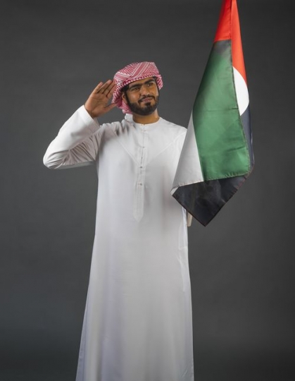 Middle Eastern man saluting carrying the UAE flag