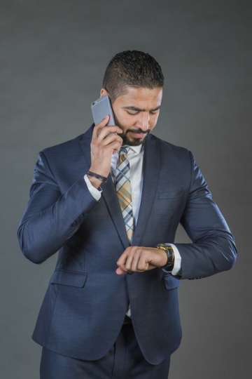 Businessman checking the time and talking on the phone|-
