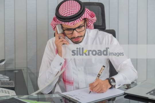 Middle Eastern Business man talking on the phone and writing |